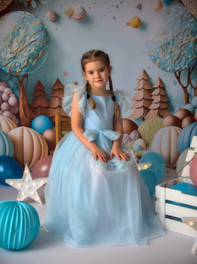 Uśmiechnięta dziewczynka w niebieskiej sukience na tle balonów